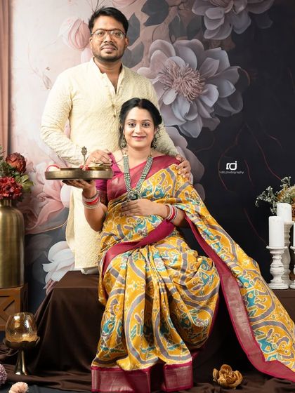 A stunning seated portrait against a floral backdrop. The couple's traditional outfits and the elegant setting create a rich and vibrant image.
