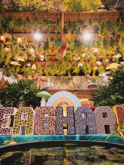 The custom "Eshaan" name display with animal-print letters, set in front of a small pond as part of the immersive jungle decoration.