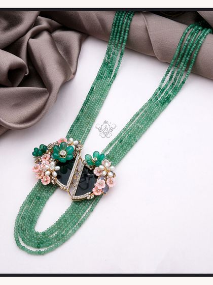 This stunning mala features multiple strands of vibrant green beads, anchored by ornate floral clasps. It is a statement piece that embodies growth and renewal, perfect for those who want their jewellery to have a deeper meaning.