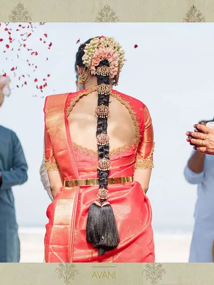 A bride on her wedding day, showcasing the back of her red blouse with a circular cutout and detailed embroidery. The design is both traditional and stylish, perfect for a modern bride.