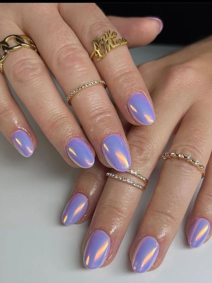 A full view of the stunning iridescent lavender chrome nails, accessorized with gold rings.