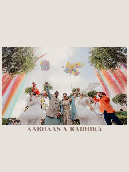 A vibrant and playful entry for Aabhaas and Radhika at their Haldi, complete with rainbow smoke and performers. This image is all about fun, color, and celebration.