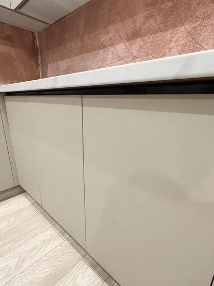 A close-up of the handleless cabinet design and the unique textured backsplash. The clean lines and combination of materials give this kitchen a very modern and custom feel.