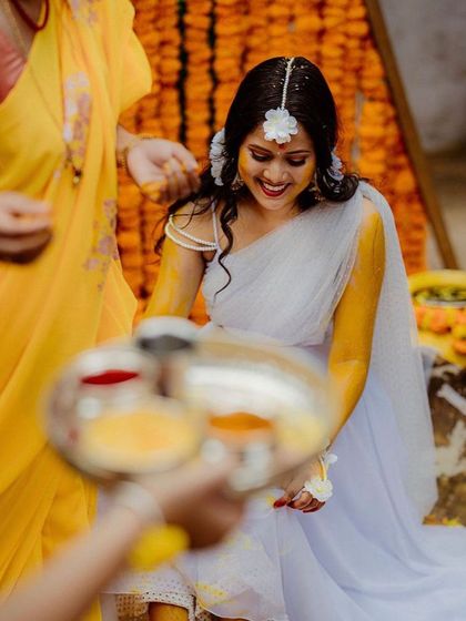 A smiling bride-to-be during her Haldi rituals. The background shows the dense wall of marigold flowers we arranged to create a bright and auspicious setting for the event.