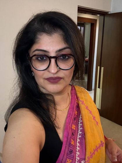 The right accessories complete any festive outfit. Here, my choice of glasses and simple jewelry complements the vibrant saree without overpowering it, ensuring a polished and thoughtful appearance.