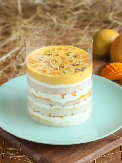 Our Mango Pull Me Up Cake in a jar format. This layered dessert is perfect for enjoying on the go, with alternating layers of sponge, cream, and mango pulp.