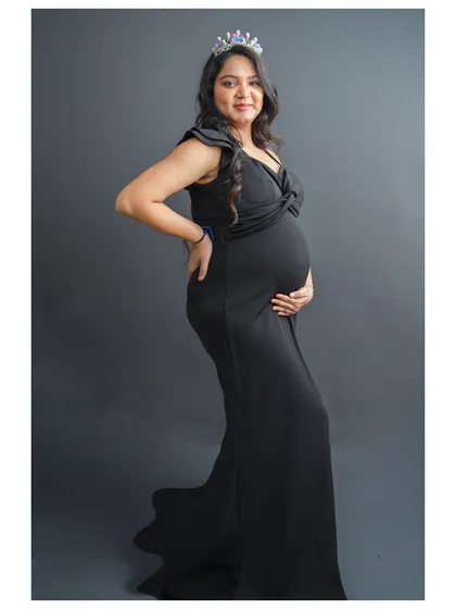 Every mother is a queen, and this portrait is designed to celebrate that. Here, the mom-to-be wears a stunning black maternity gown and a delicate crown, creating a timeless and empowering solo portrait against a classic studio backdrop.