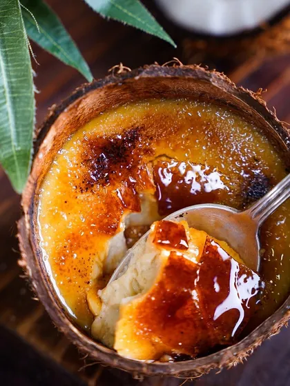 A spoonful of our creamy, decadent Crème Caramel. This dessert is a testament to our mastery of classic international sweets.