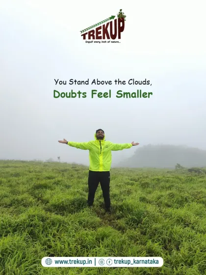 A trekker stands with arms outstretched in a vast, misty green meadow. The caption says, "You stand above the clouds, doubts feel smaller."