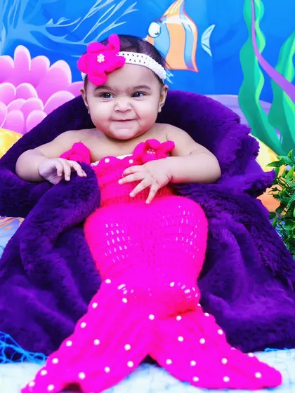A smiling close-up of the baby mermaid, showing her cute expression and detailed costume.