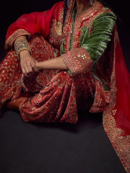 A detailed shot focusing on the lower half of a Debyani & Co outfit, highlighting the intricate embroidery on the pants and sleeves.