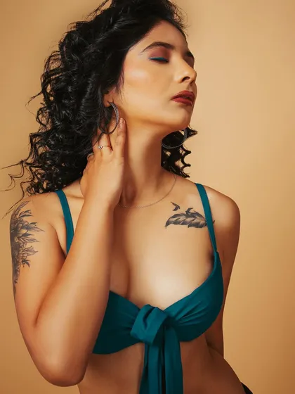 A serene, eyes-closed pose that highlights the model's tattoos and the fit of the top, creating a relaxed and artistic feel.