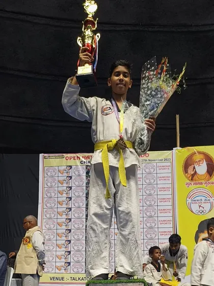 This young student is thrilled to be on the podium with his trophy and bouquet after a great performance.