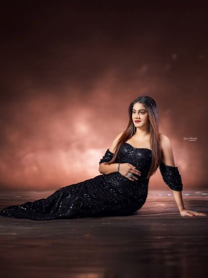 A relaxed, seated pose on the floor, with the sparkling black gown catching the light beautifully.