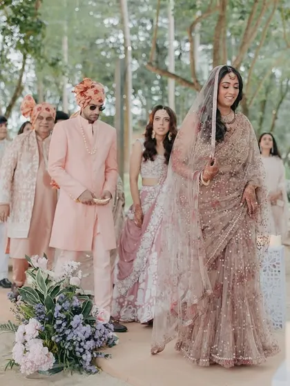 The bride's graceful entrance through a path lined with trees and candles. This shot captures the anticipation and elegance of the bridal procession.
