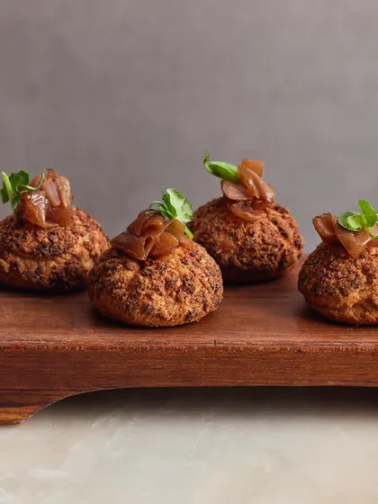 A close-up of our Chicken Liver Parfait Choux Buns, showing the crispy craquelin topping and the rich onion jam.