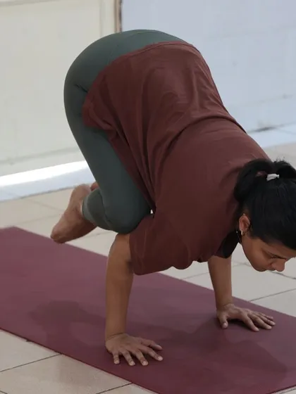 A student holds the crow pose with deep concentration. Arm balances like this improve focus and build confidence.