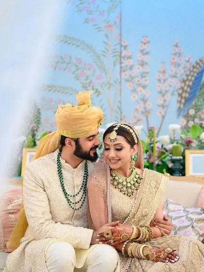 A lovely couple sharing a moment against a pastel blue, hand-painted backdrop. Their coordinated pastel outfits perfectly complement the soft and romantic decor of their dream wedding.