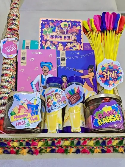 Holi is the festival of colors, and the gifts should be just as vibrant. This festive hamper is packed with everything needed for a fun celebration, including herbal gulaal from Phool, thandai bottles, water balloon pumps, and other playful goodies, all arranged in a decorated tray.