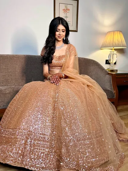 The full view of the sparkling golden reception lehenga. The makeup is kept soft and chic to balance the shimmer of the outfit.