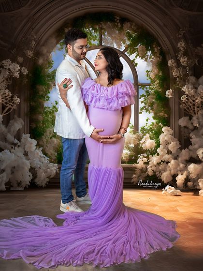 An elegant embrace in a dreamy, flower-filled studio. This portrait captures the romance and magic of expecting a child together.