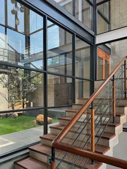 A view of the staircase at the 6AM House, seen through a wall of glass. The design emphasizes transparency, allowing views through the building and out into the garden from multiple points.