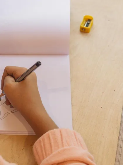 A close-up of Samara's hand as she carefully sketches. Our art classes help develop fine motor control and an eye for detail.