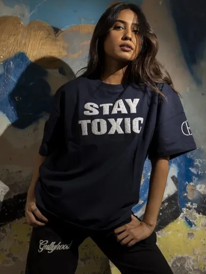 A powerful portrait of a model in an oversized graphic tee. The hard lighting and gritty background enhance the "toxic" slogan, perfectly capturing the brand's bold attitude.