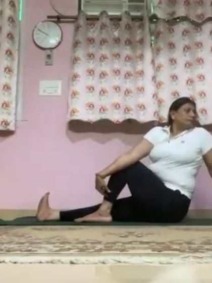 An instructor demonstrates Ardha Matsyendrasana (Half Lord of the Fishes Pose), a seated spinal twist. This pose is excellent for improving spinal flexibility and aiding digestion.
