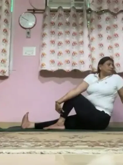 An instructor demonstrates a seated spinal twist. This pose, Ardha Matsyendrasana, massages the abdominal organs and improves flexibility in the spine.