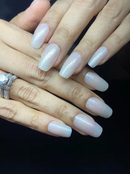 A simple yet glamorous set of long, coffin-shaped nails with a glittery beige nude polish.