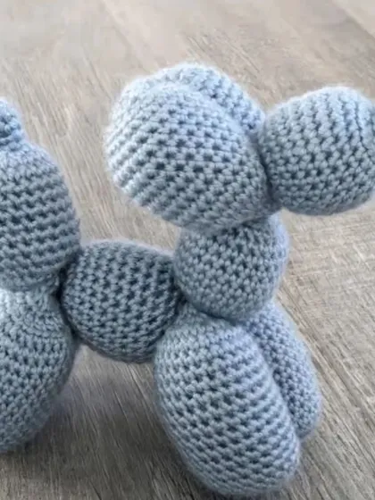 A single crochet balloon dog in a lovely grey-blue color, showing the clever construction that mimics a real balloon animal.
