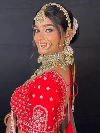 A beautiful close-up of a bride in a red lehenga, highlighting the stunning bridal jewelry, including the nath and choker necklace.