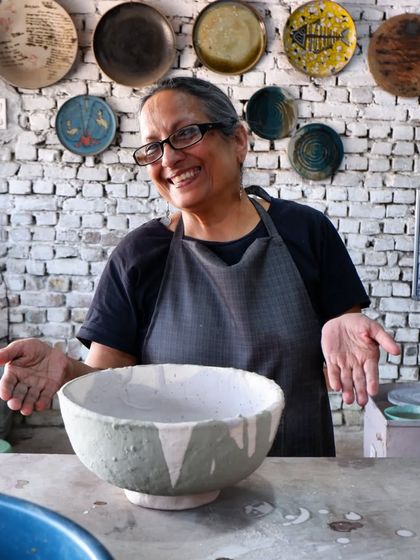 The joy of creation! A student proudly shows off her large, hand-built bowl, now ready for the magic of the Raku kiln.