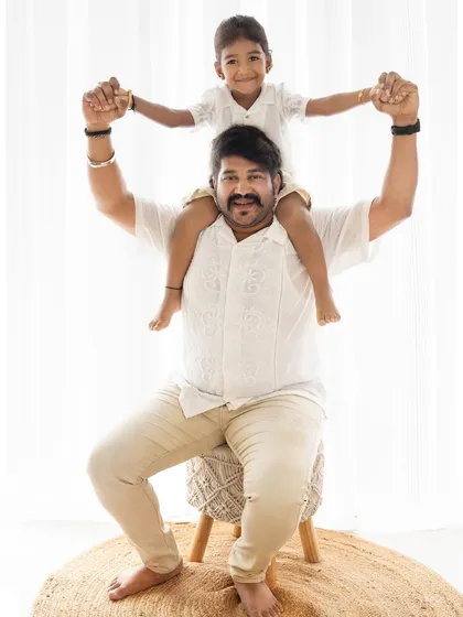 A proud father with his son on his shoulders. This classic "daddy and me" pose is full of strength and joy, set against a clean, bright background.
