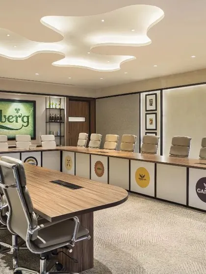 The main boardroom at the Carlsberg head office in Gurugram, a space that embodies brand legacy and sustainability. The design features a custom glass mosaic logo made from recycled Carlsberg bottles and a suspended hop symbol, translating corporate identity into a tangible, inspiring environment.
