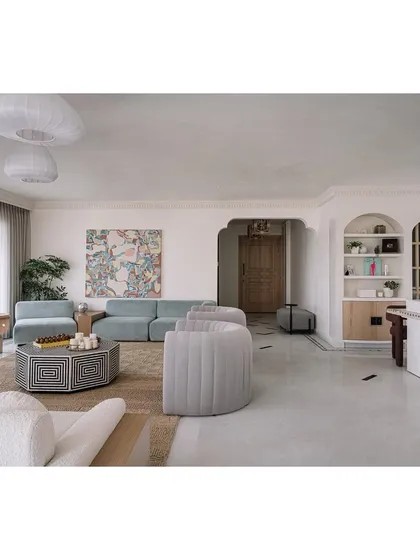The main living area is a study in color, texture, and form. A powder blue sofa, lilac armchairs, and a custom painting referencing the family's travels create a space that is vibrant and full of life.