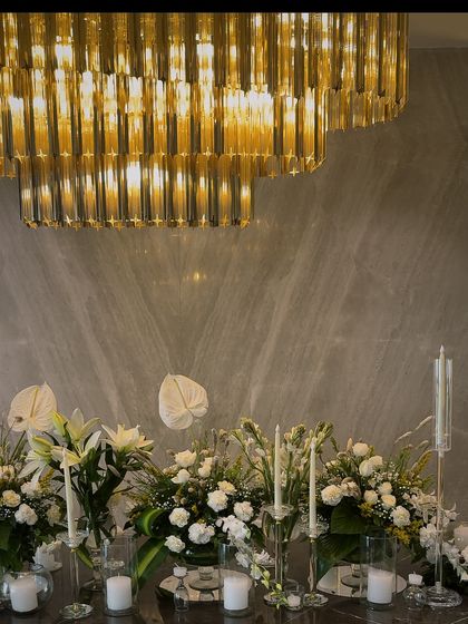 A wide shot of the Diwali dining table, showcasing the grand scale of the floral arrangement under the magnificent gold chandelier.