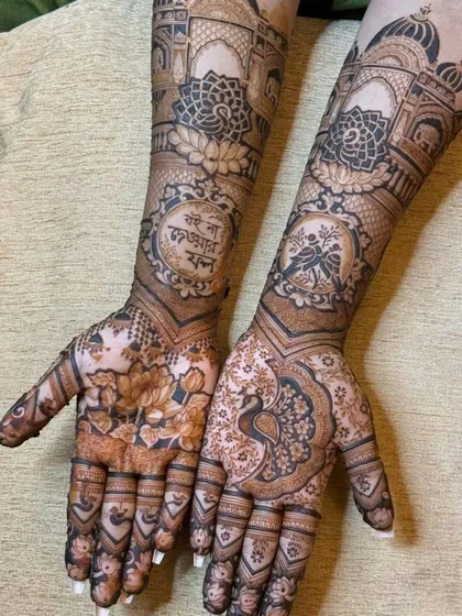 A mix of floral and architectural elements. This design includes lotus patterns, peacocks, and palace-style domes, with a special message written in Hindi on the forearm.