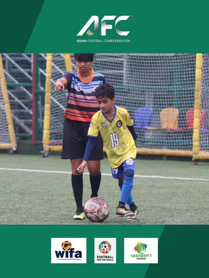An older player guides a younger one during a drill at the AFC Grassroots Day, embodying our mentorship culture.