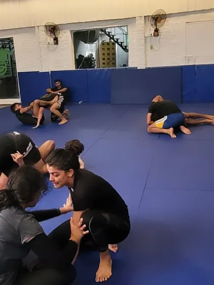 A female student works to pass the guard of her training partner. Our classes are fully integrated, with men and women of all skill levels training together and helping each other improve.