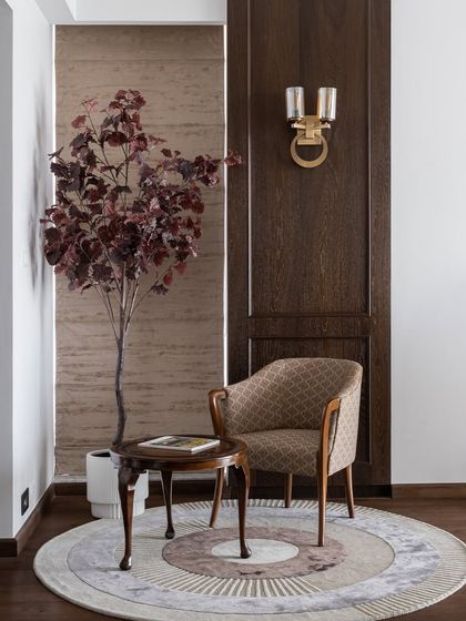 A cozy reading corner in a bedroom, featuring a classic armchair and a small wooden table. The warm wood tones and indoor plant create a peaceful spot to relax and unwind.