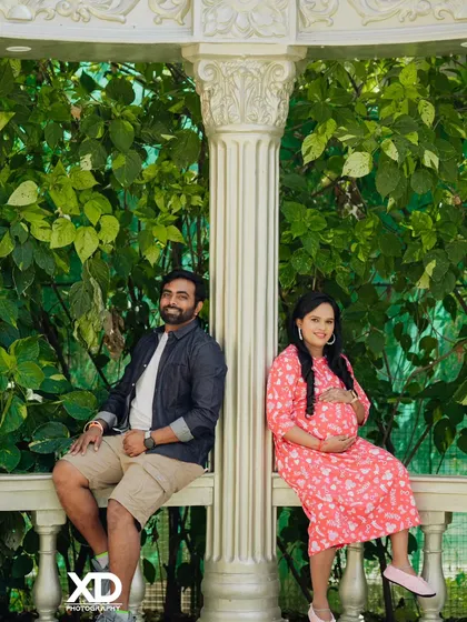 A relaxed portrait of a couple sitting on either side of a pillar, creating a sense of connection and space.