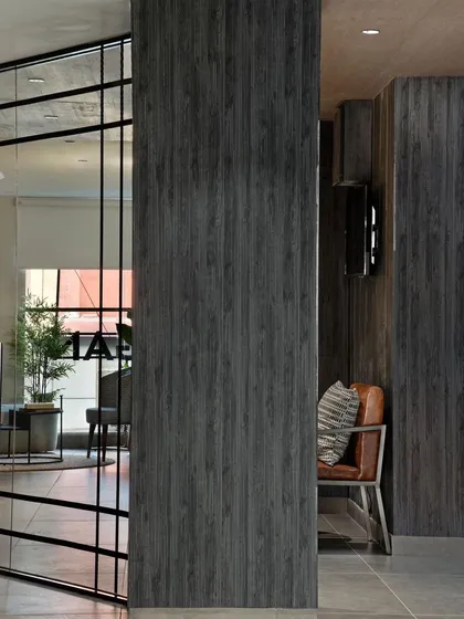 A detail shot of the office corridor, highlighting the texture of the dark wood paneling and the industrial-style glass and metal door.