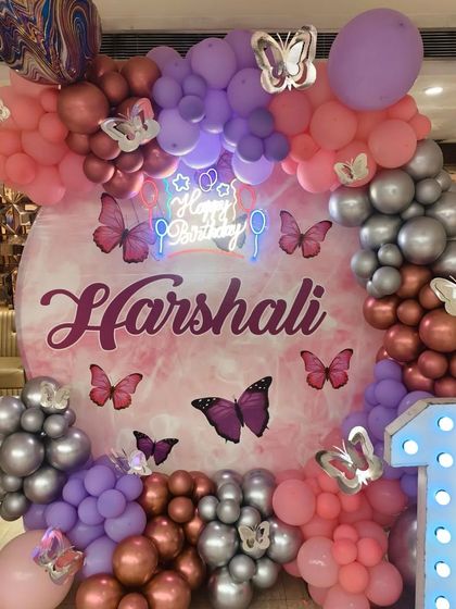 A close-up of the main backdrop for the butterfly party, featuring a custom print, a neon sign, and a beautiful balloon arch.