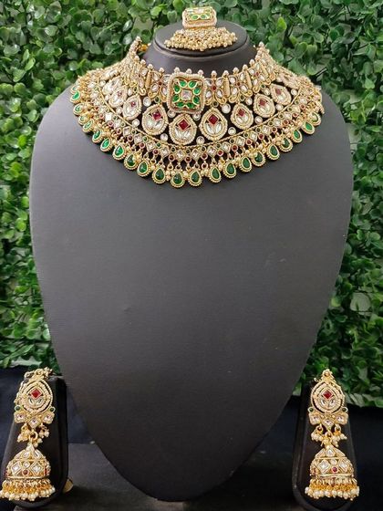 A classic red and green kundan choker set with matching jhumkas and maang tikka.
