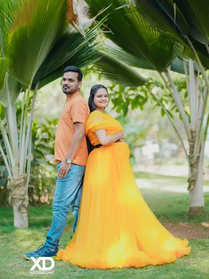 A classic back-to-back pose for a couple in a beautiful garden, surrounded by palm trees.