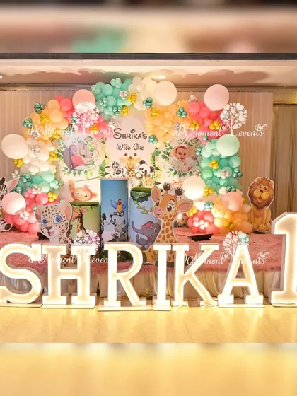 Another view of the "Wild One" jungle stage, showcasing the full arrangement of balloons, marquee letters, and animal props on a pink carpeted stage.