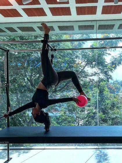 Your presence should brighten the surroundings. This inverted pose on the Cadillac, incorporating the small stability ball, adds a layer of challenge and playfulness.