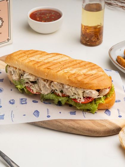 My Pulled Chicken Pan Bagnat is a hearty sandwich filled with spicy, tender pulled chicken and fresh vegetables in a soft, round pan bagnat bread.